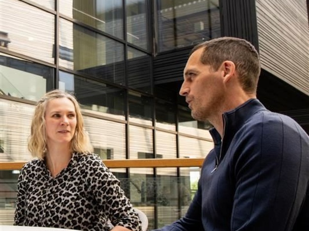A man and woman talking outside a glass building