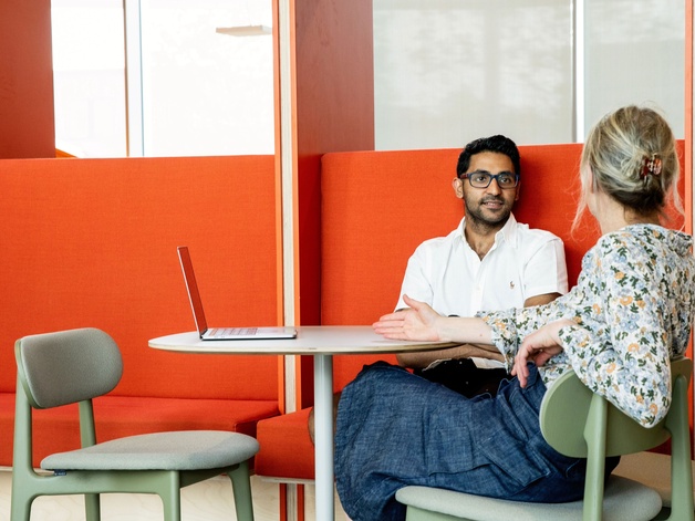 A man and a woman in an orange coloured booth, talking